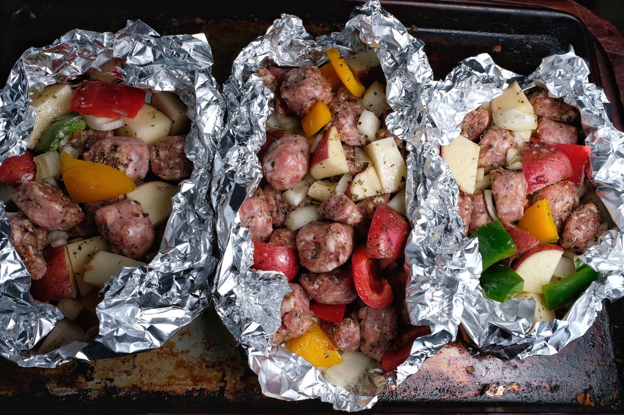 3 foil packet dinners with sausage, potatoes, and peppers