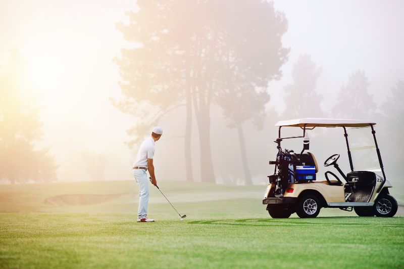 Old Man Golfing Next To Golf Cart