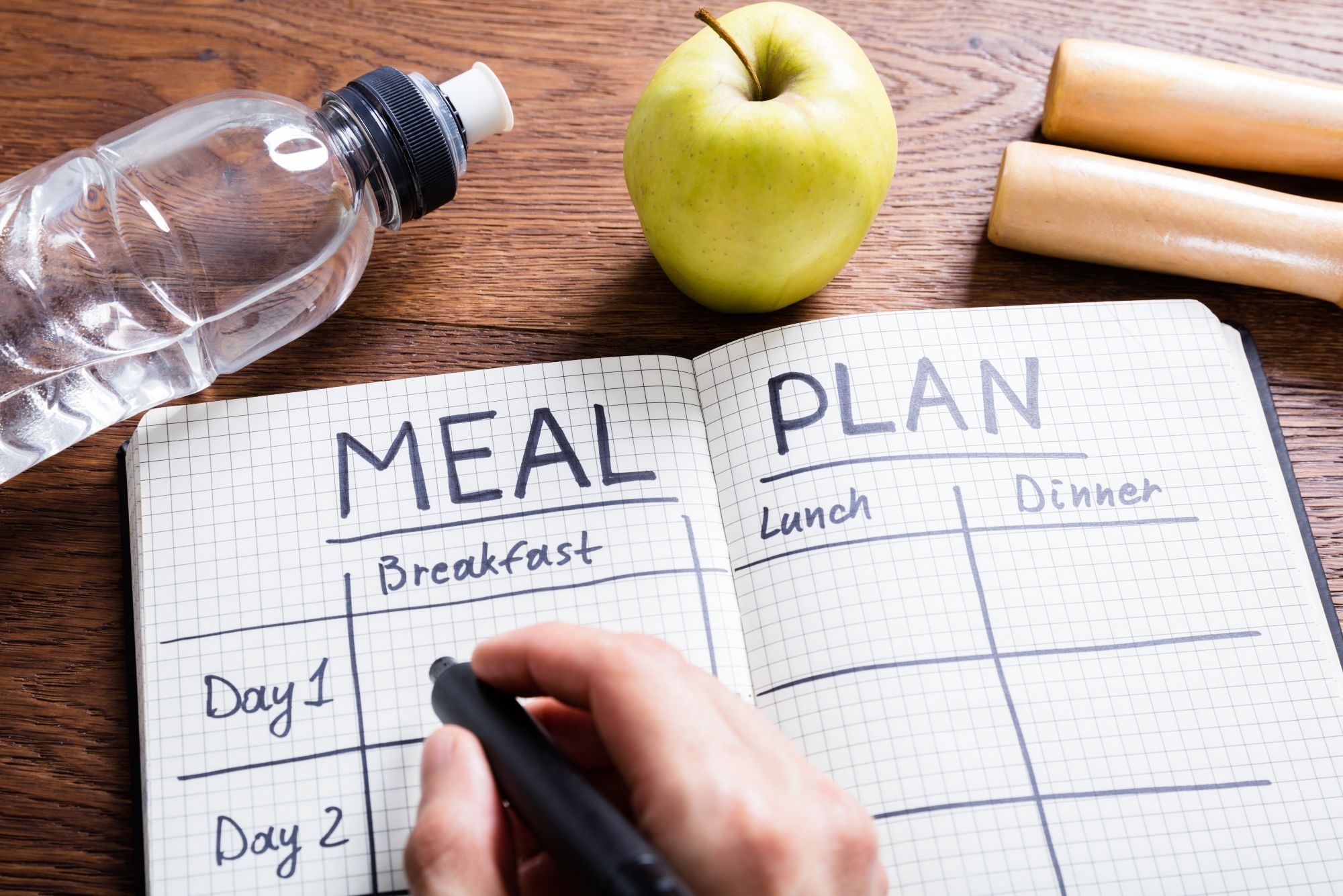 meal planner notebook with water bottle and apple