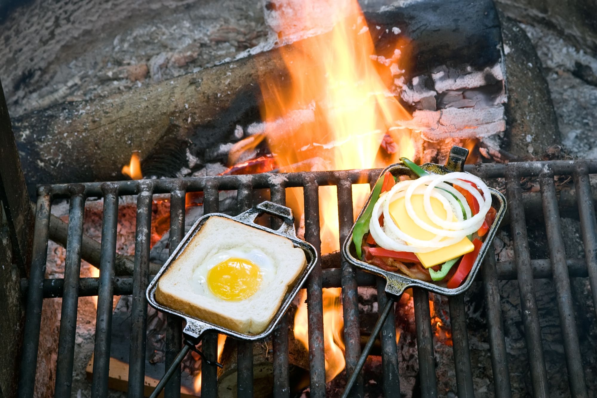 an open pie iron cooking a breakfast sandwich