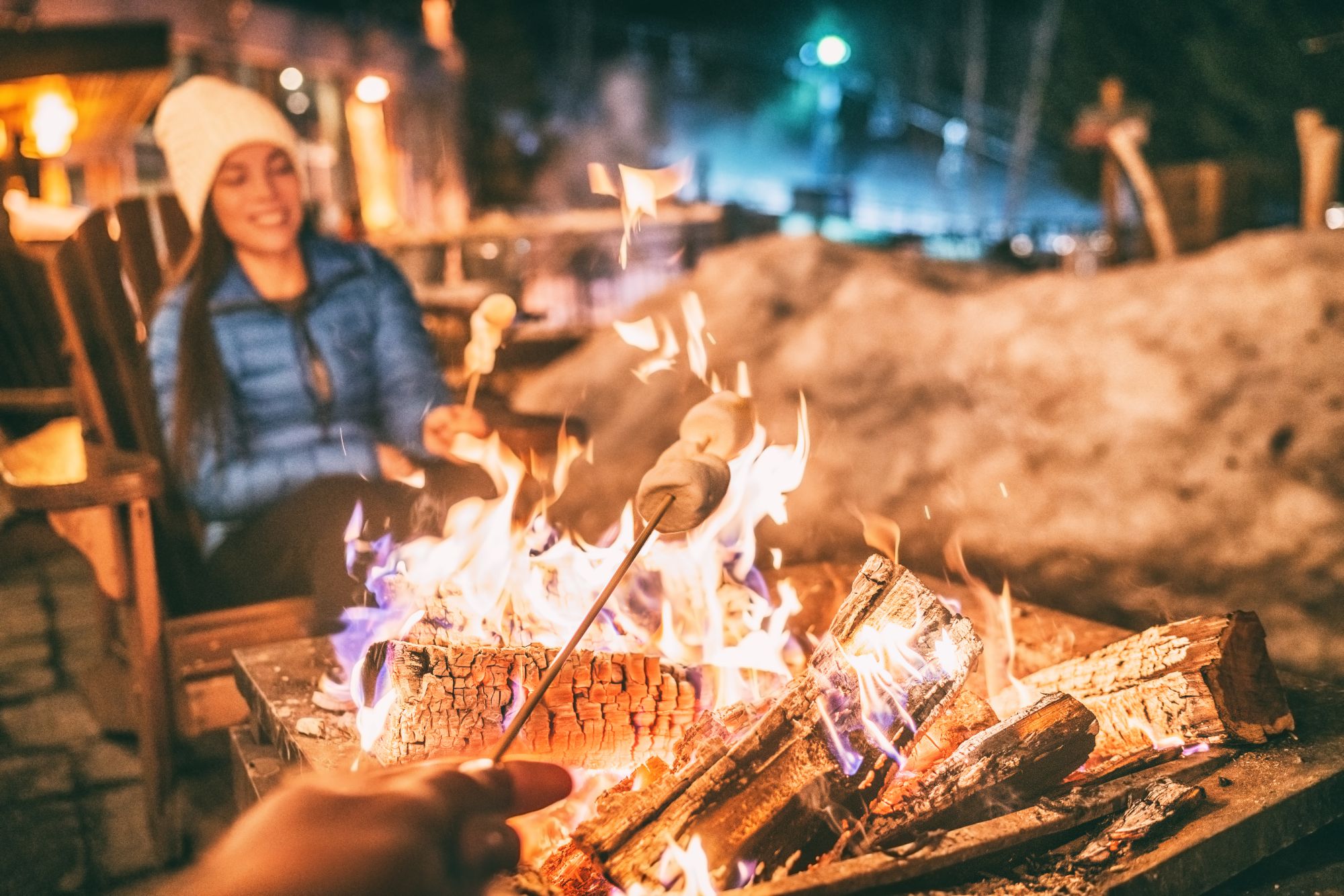 A campfire during winter with two people roasting marshmallows 