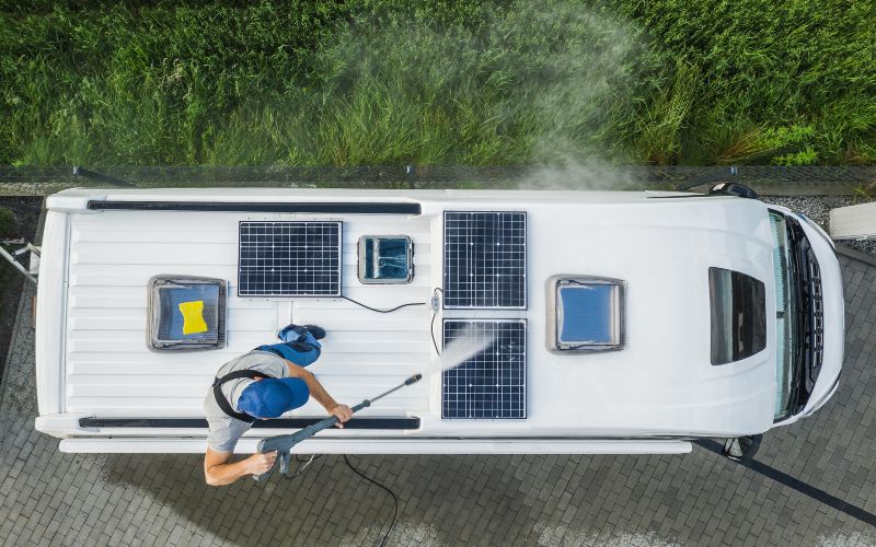 A man power washing the solar panels on top of his camper van
